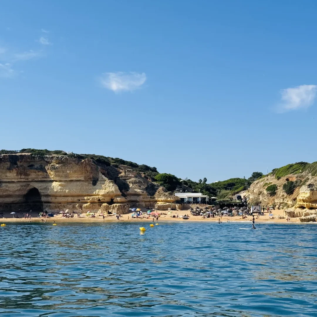 Algarve beach with limestone cliffs, sea cave and sunbathers seen from the water