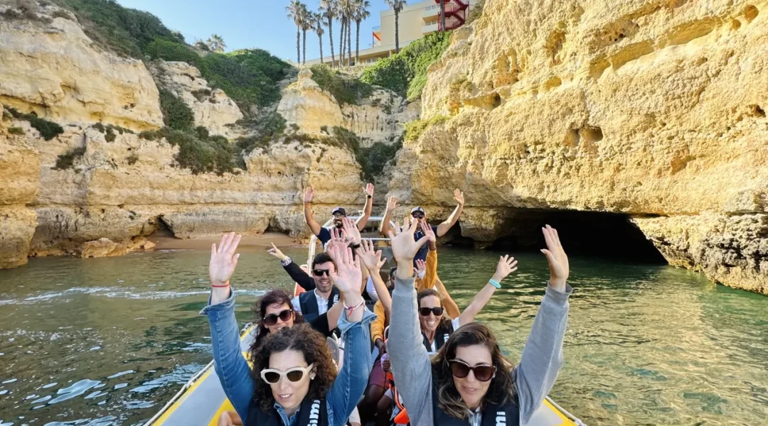 Otter Tours guests raising their arms in excitement aboard the boat with Algarve rock formations in the background